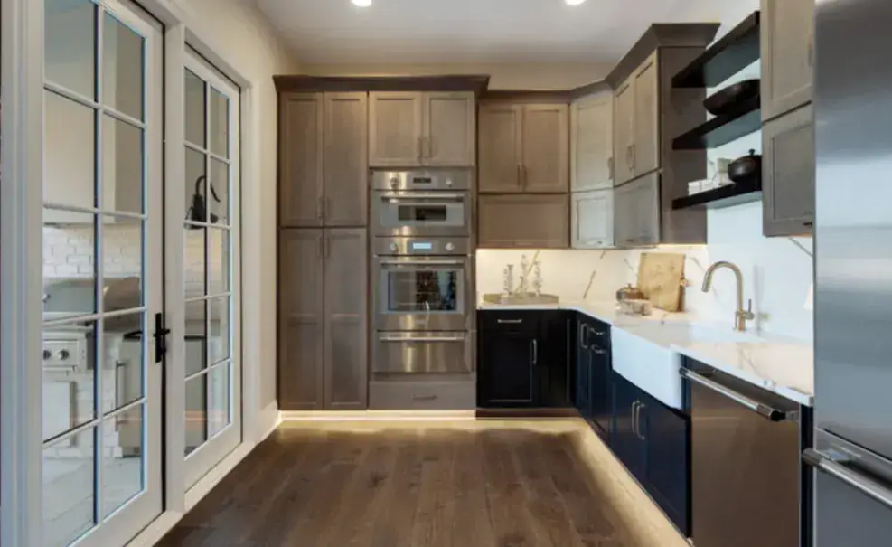 Two-tone kitchen with driftwood oven-wall cabinets, navy lowers, apron sink, open shelves and toe-kick lighting