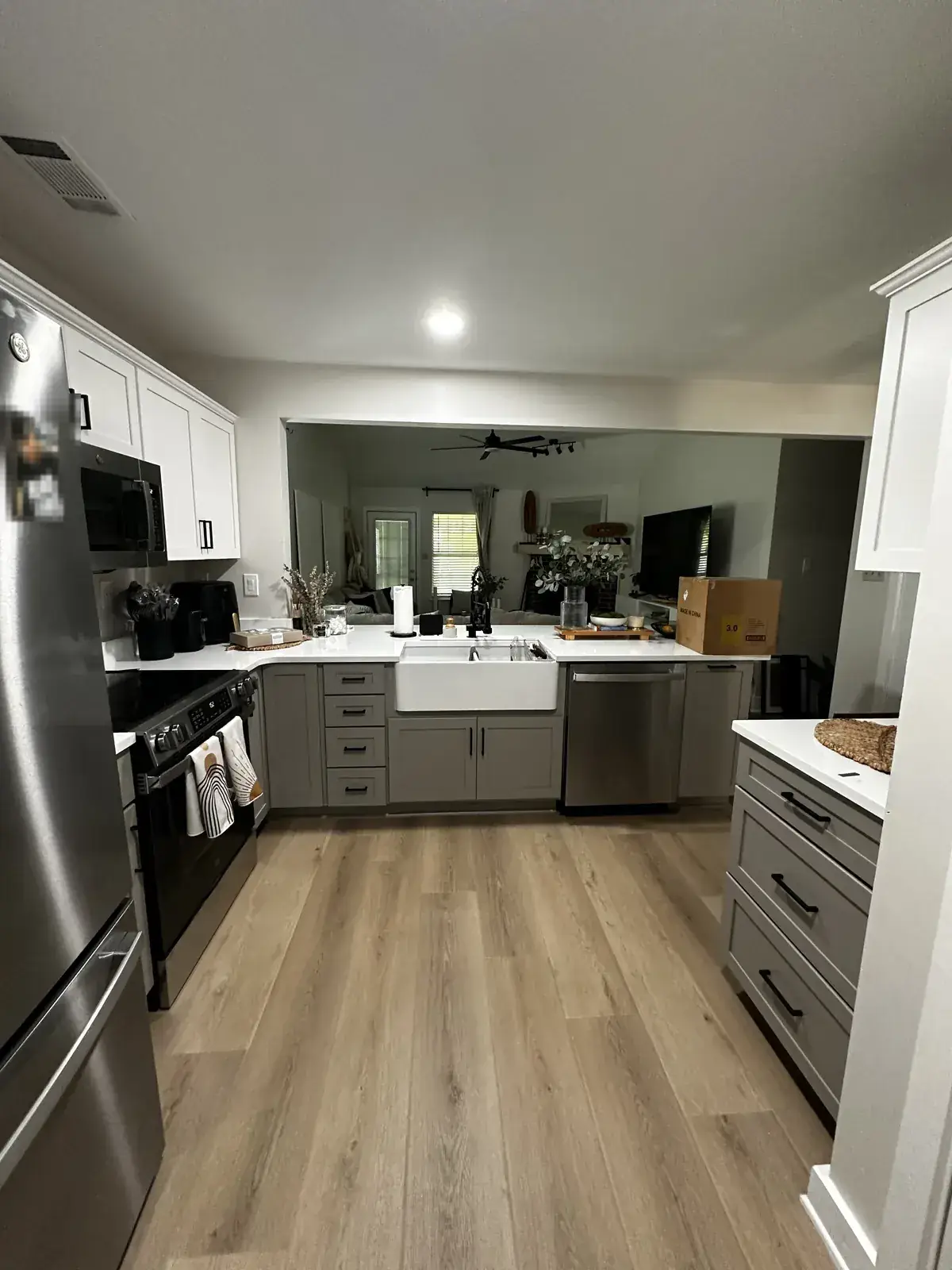 Completed kitchen remodel: white shaker cabinets, quartz counters, farmhouse sink, stainless appliances, LVP flooring